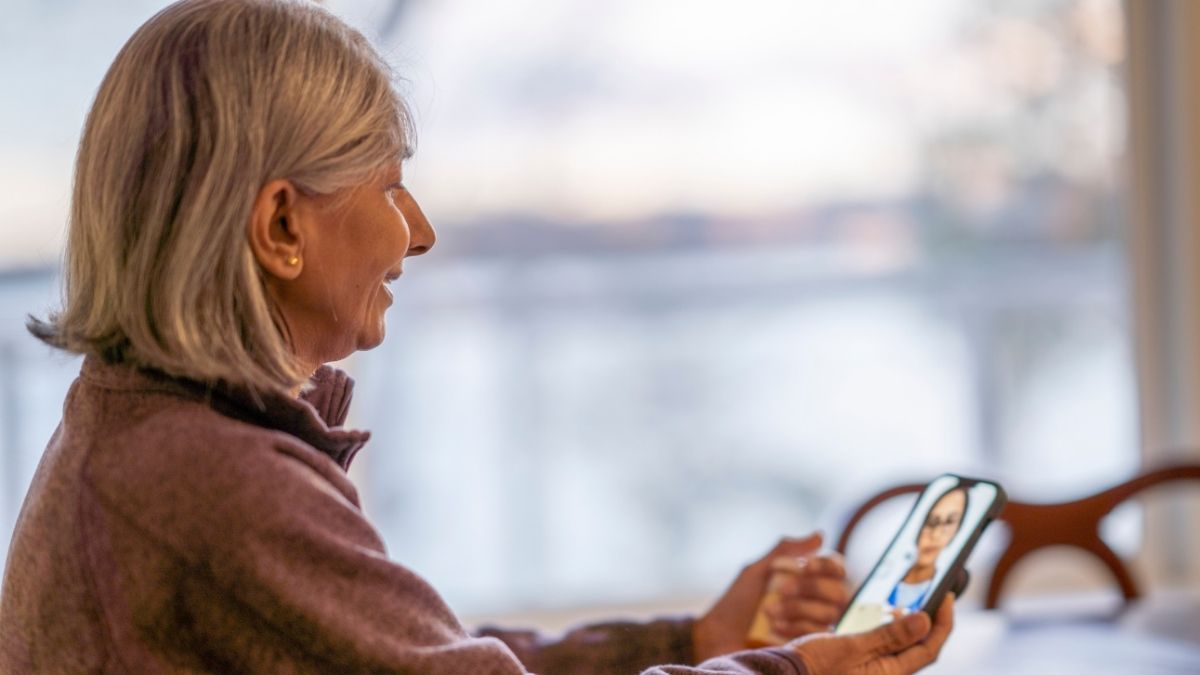 Senior woman having a video consultation with a Medi-Share provider on her smartphone at home.