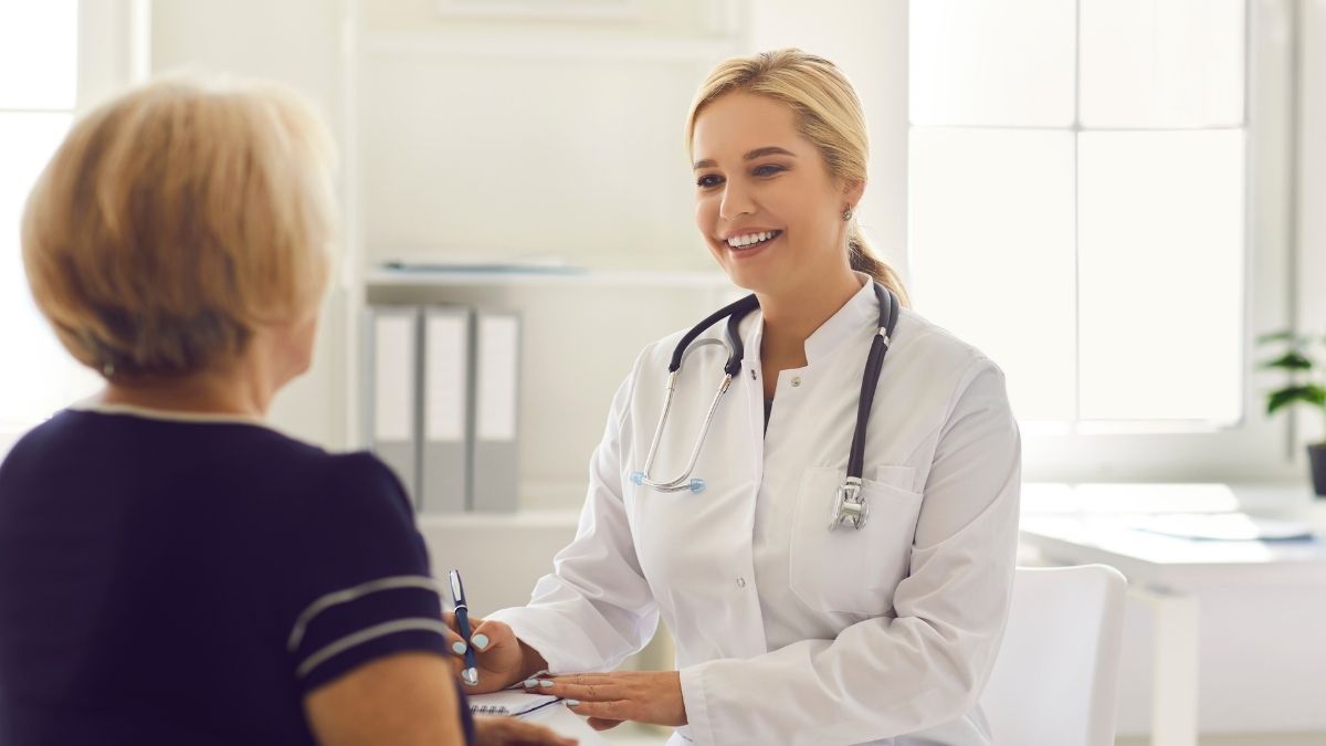 Smiling doctor consulting with a senior patient in a medical office, representing concerns over the Medicare premium increase.