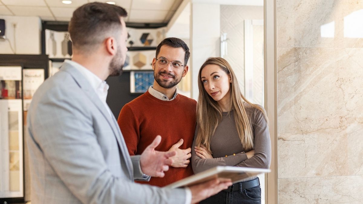 A couple discussing insurance options with an agent in a showroom, representing United of Omaha Medicare Supplement consultation.