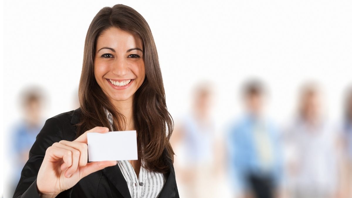 Smiling woman holding a blank card representing a Medicare card, illustrating the question can you laminate your Medicare card.