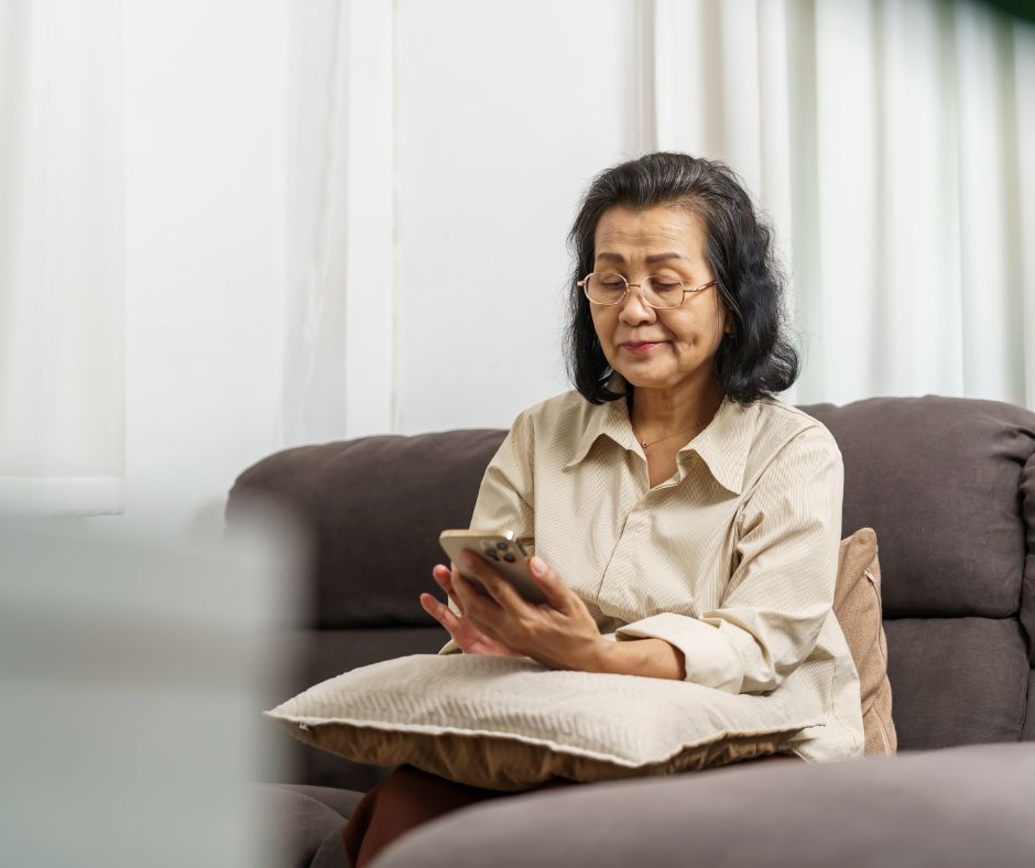 Older woman sitting on a couch and looking at her phone
